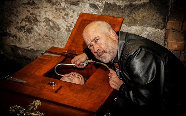 Man performing magic trick with a woman in a coffin on the Dublin Ghostbus Tour.