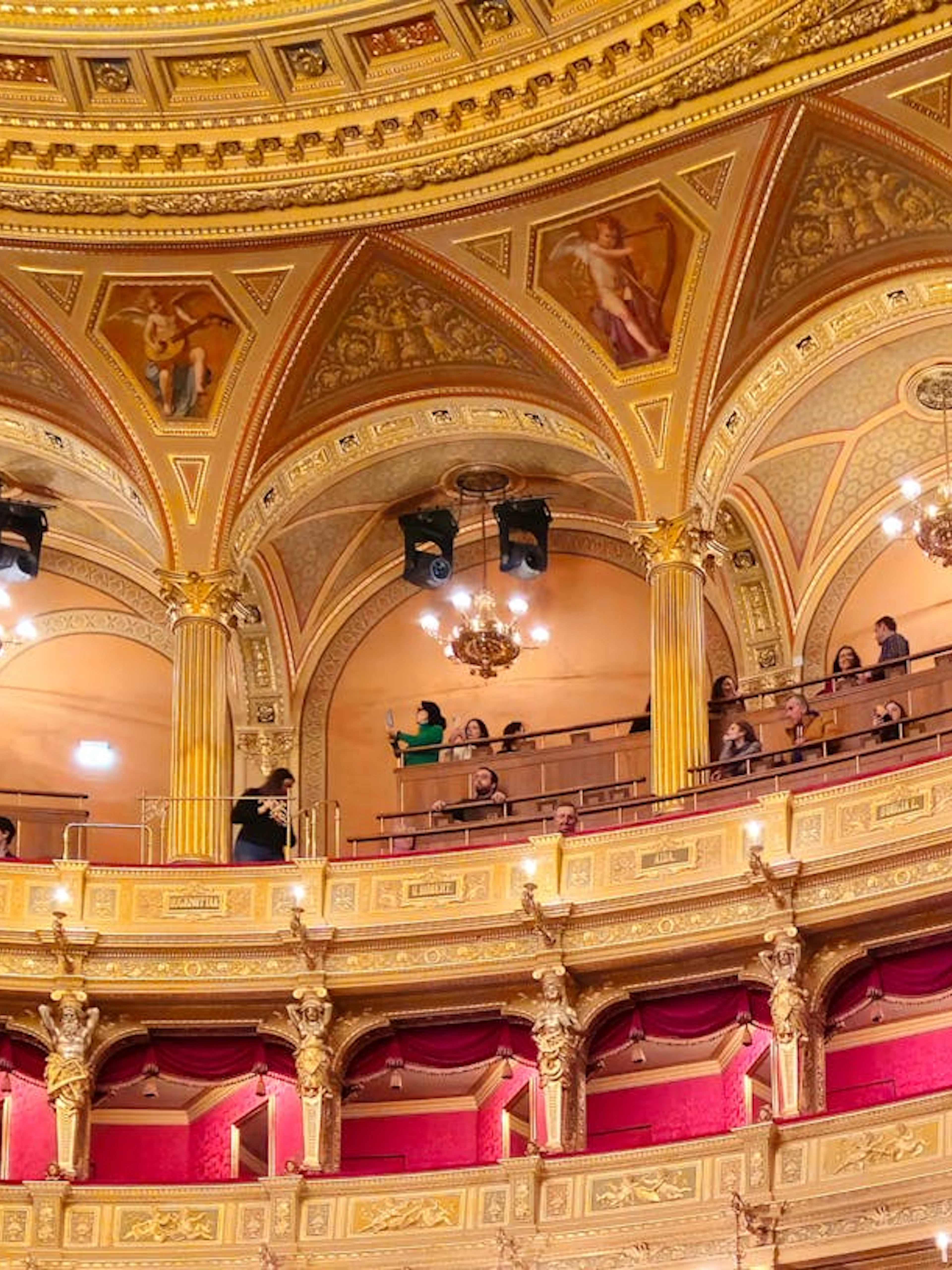 Hungarian State Opera House interior with ornate balconies and visitors during a guided tour.
