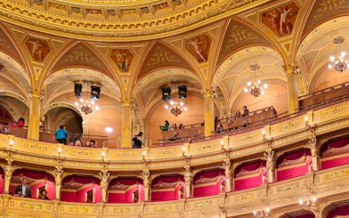 Hungarian State Opera House interior with ornate balconies and visitors during a guided tour.