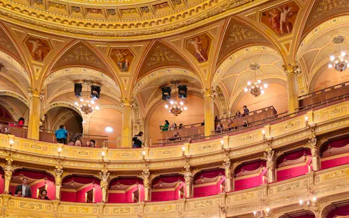 Hungarian State Opera House interior with ornate balconies and visitors during a guided tour.