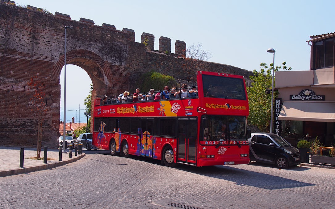 Thessaloniki hop-on hop-off bus near ancient city wall arch.