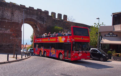 Thessaloniki hop-on hop-off bus near ancient city wall arch.