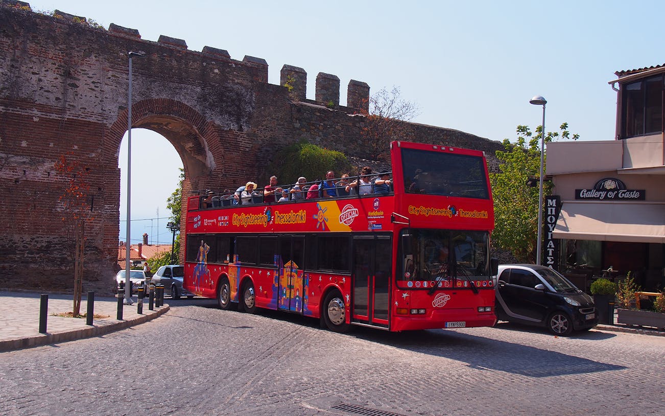 Thessaloniki hop-on hop-off bus near ancient city wall arch.