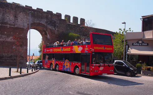 Thessaloniki hop-on hop-off bus near ancient city wall arch.