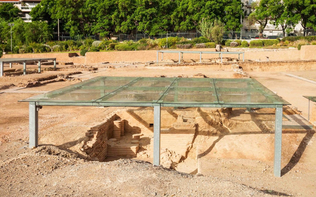 Ancient ruins under glass cover at Acropolis site in Athens.