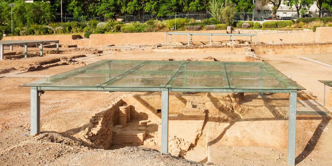 Aristotle's Lyceum ruins in Athens, Greece, surrounded by lush greenery.