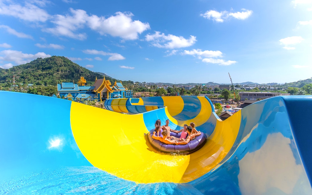 People enjoying a water slide at Andamanda Phuket with scenic views.