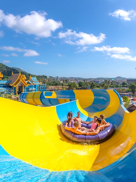 People enjoying a water slide at Andamanda Phuket with scenic views.