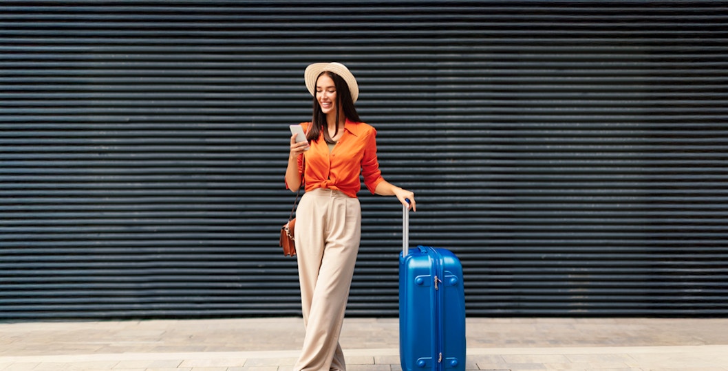 Female traveler with luggage at the Eiffel Tower, Paris, France.