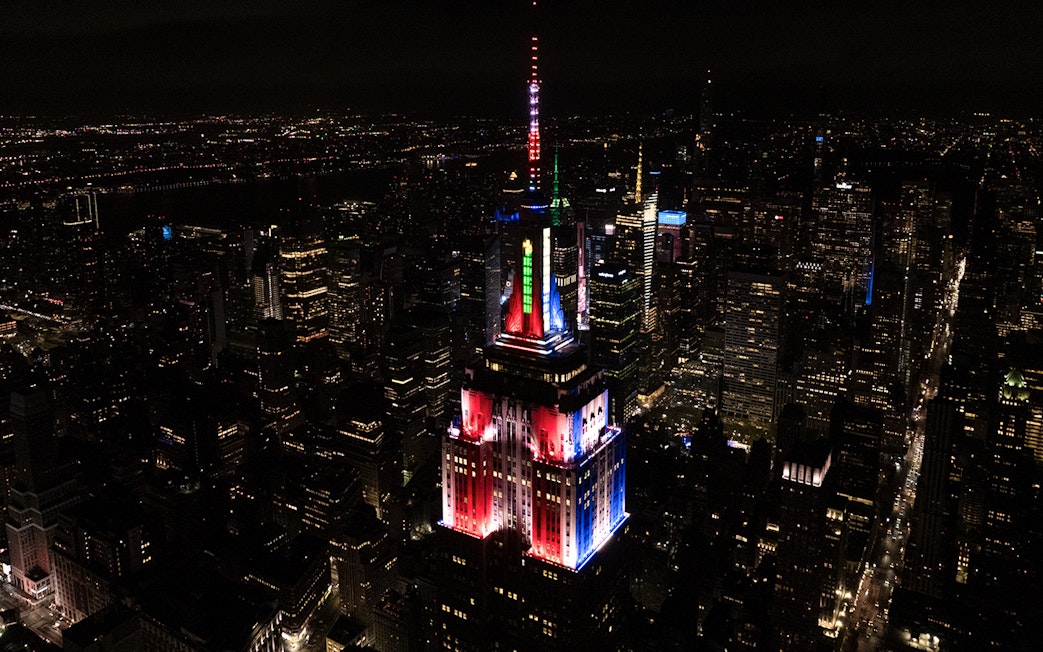 Empire State Building lit in Christmas colors, New York City skyline at night.