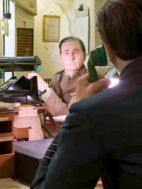 Man in military uniform at desk with vintage telephones, Churchill War Rooms tour.