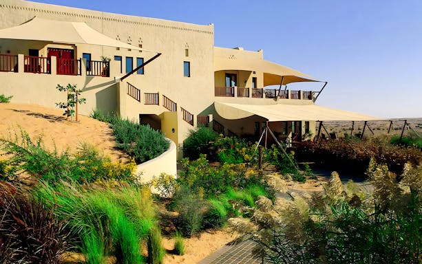 Al Maha Desert Resort villa with desert landscape and greenery.