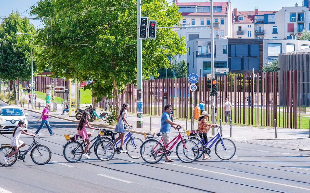 Cyclists crossing street near Berlin Wall on guided bike tour.