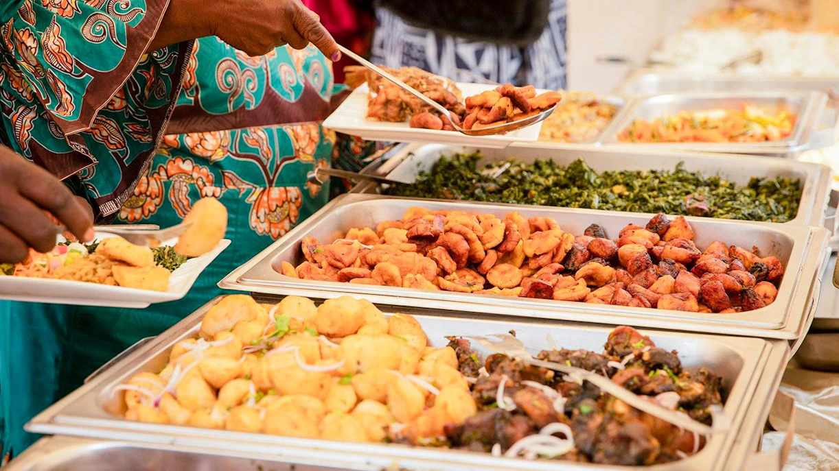 Buffet with fried plantains, potatoes, meat, and vegetables at a Nairobi party.