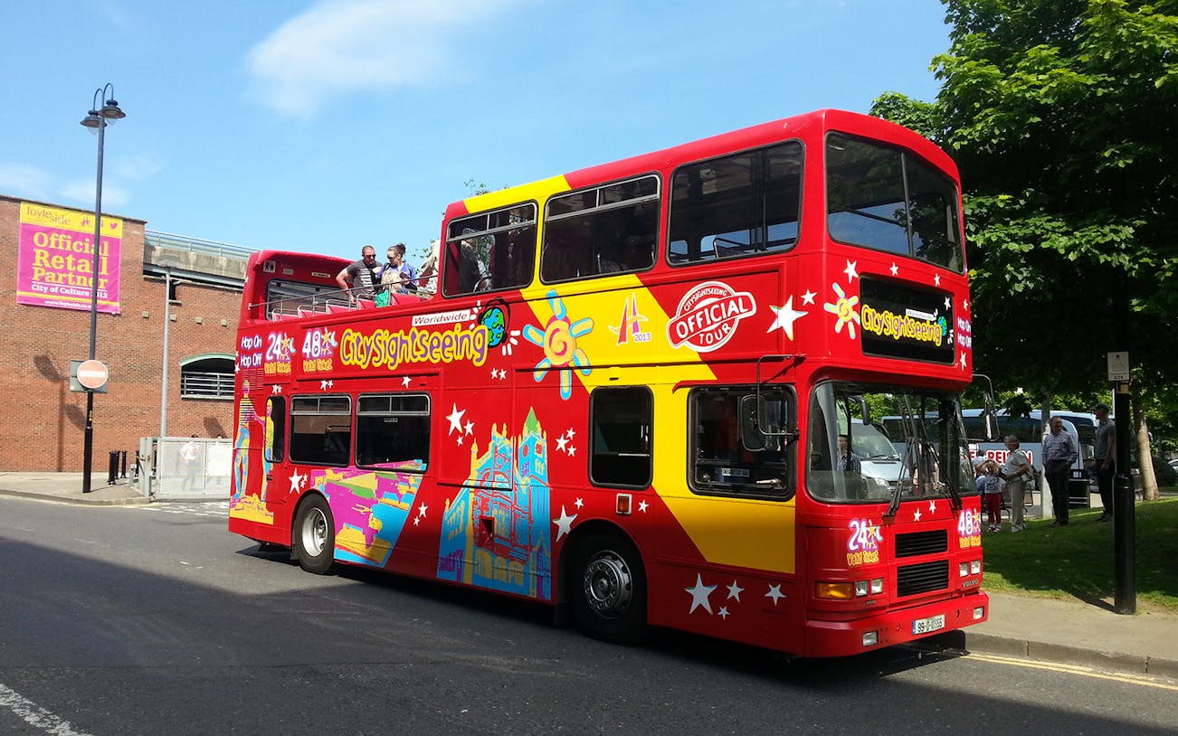 Red double-decker bus for Derry Hop-On-Hop-Off Tour with passengers on top deck.