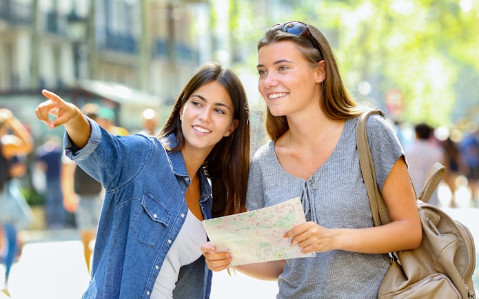 Two women exploring Oxford with a map, pointing towards a landmark.