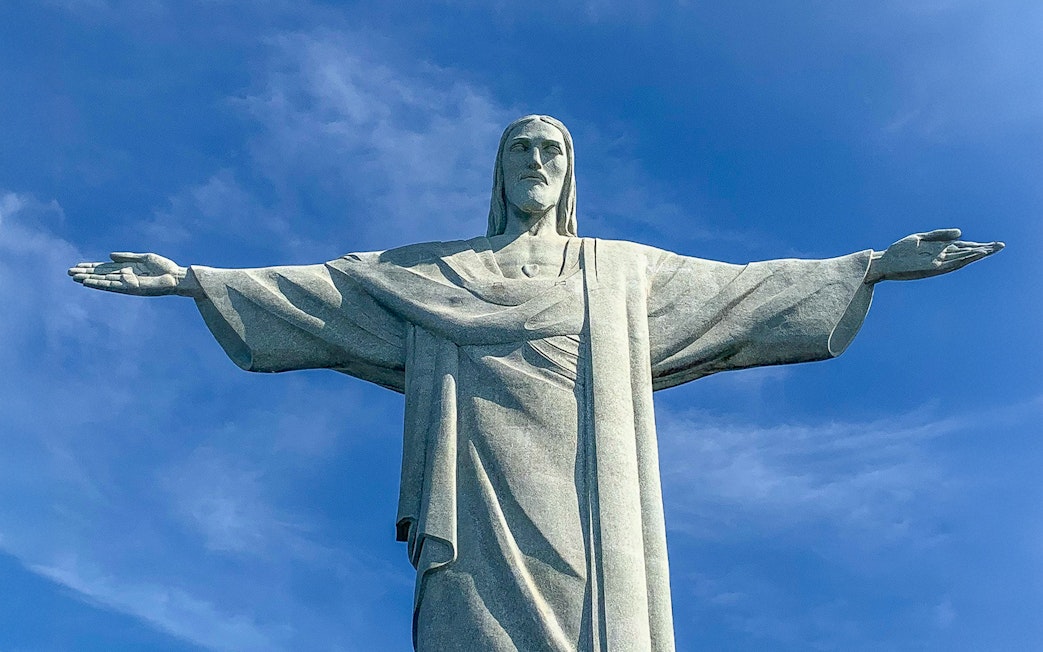Christ the Redeemer statue with arms outstretched against blue sky, Rio de Janeiro.