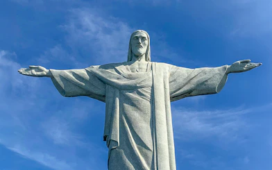 Christ the Redeemer statue with arms outstretched against blue sky, Rio de Janeiro.