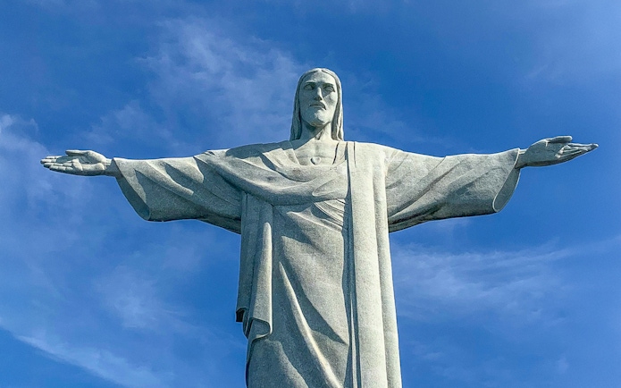 Christ the Redeemer statue with arms outstretched against blue sky, Rio de Janeiro.