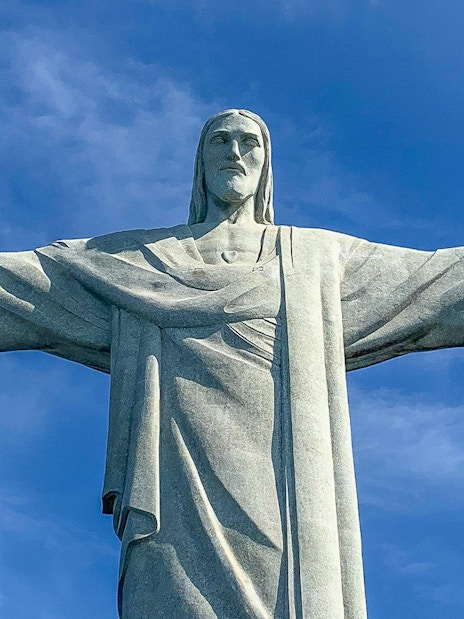 Christ the Redeemer statue with arms outstretched against blue sky, Rio de Janeiro.