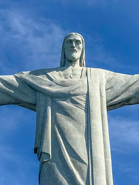 Christ the Redeemer statue with arms outstretched against blue sky, Rio de Janeiro.
