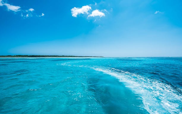 Cruising on Ishigaki Island's turquoise sea with distant shoreline.