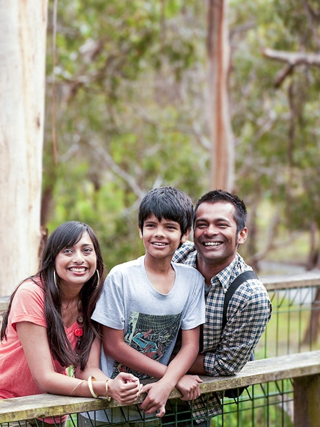 Family smiling near a koala at Koala Conservation Reserve, Phillip Island.