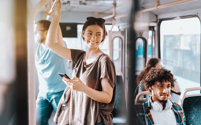 Passengers on Edinburgh Airport Transfer bus, one standing with phone, others seated.