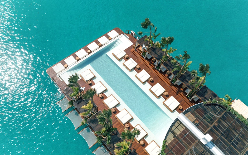 Private cabanas and pool at Yona Beach Club, Phuket, overlooking turquoise water.