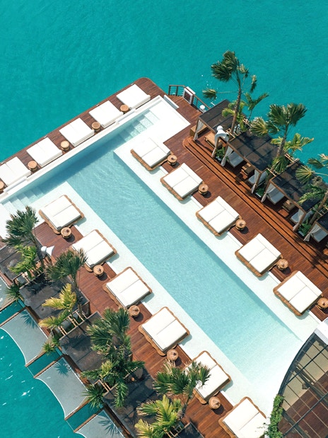 Private cabanas and pool at Yona Beach Club, Phuket, overlooking turquoise water.