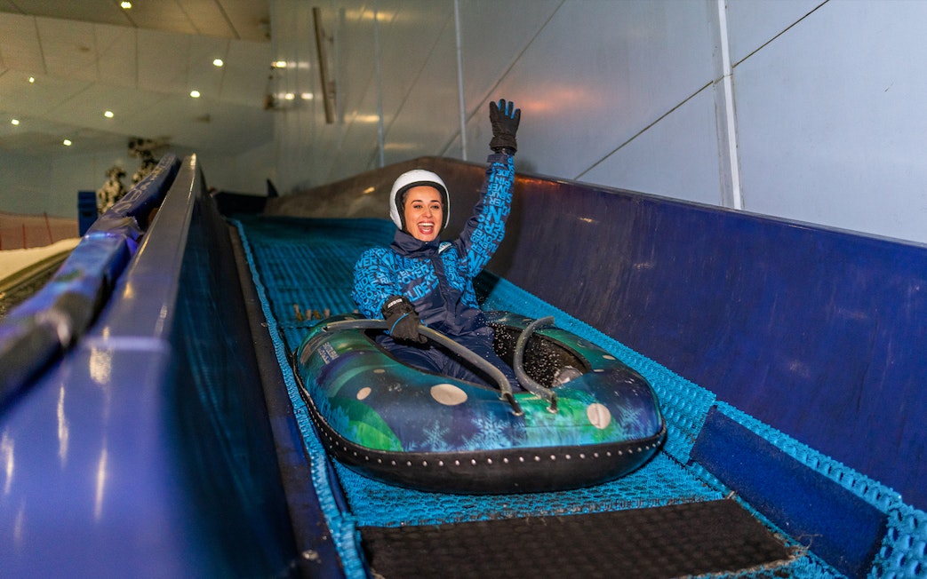 Woman tubing down a slope at Ski Dubai Snow Park.