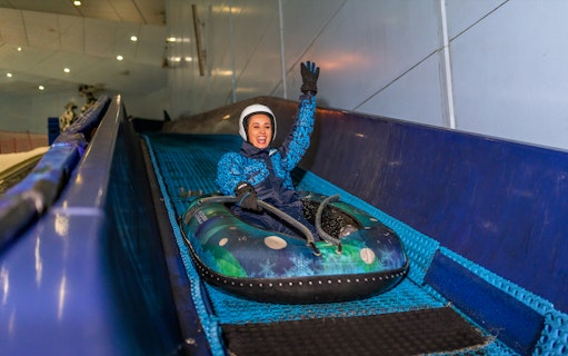 Woman tubing down a slope at Ski Dubai Snow Park.