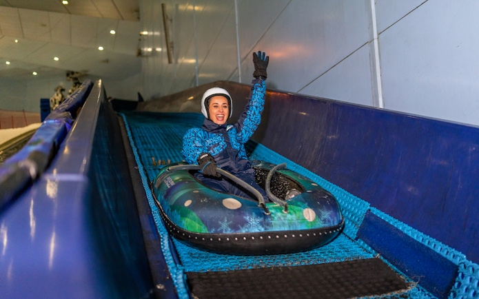Woman tubing down a slope at Ski Dubai Snow Park.