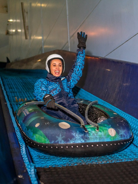 Woman tubing down a slope at Ski Dubai Snow Park.