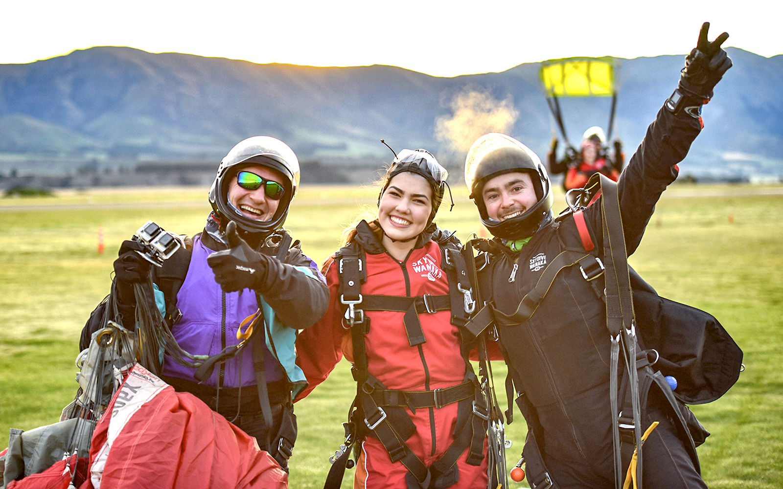 Skydivers celebrating after a tandem jump in Wanaka with mountains in the background.