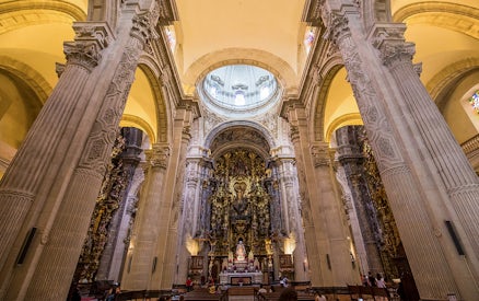 Seville Cathedral interior with ornate altar and towering columns.