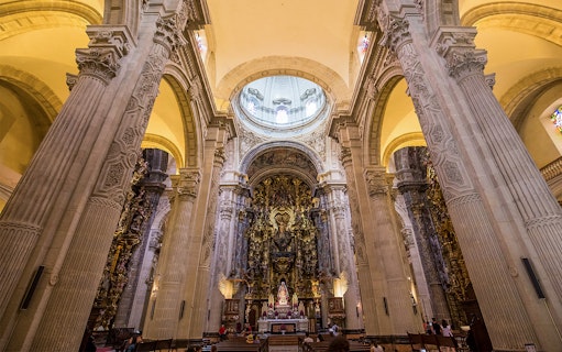Seville Cathedral interior with ornate altar and towering columns.