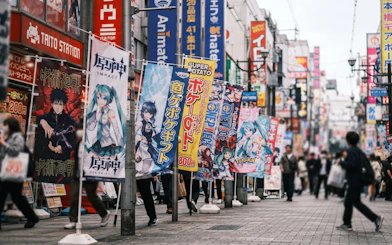 Street view of Osaka's Den Den Town with anime and game shop banners.