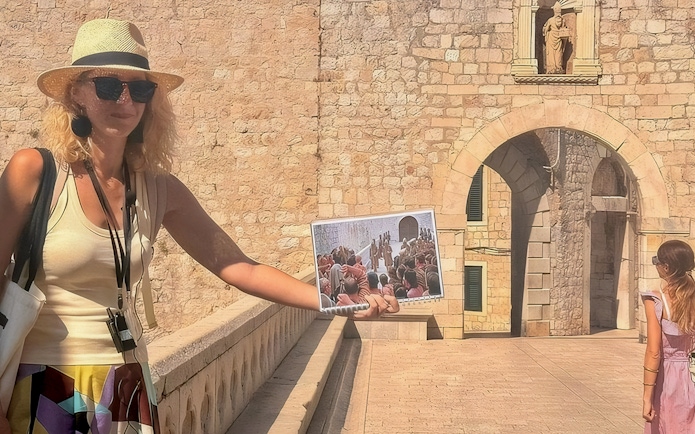 Female guide showing Game of Thrones filming location to tourists in Dubrovnik.