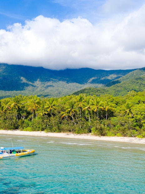 Boat near tropical shoreline with mountains, Great Barrier Reef Guided Snorkel & Eco Tour.