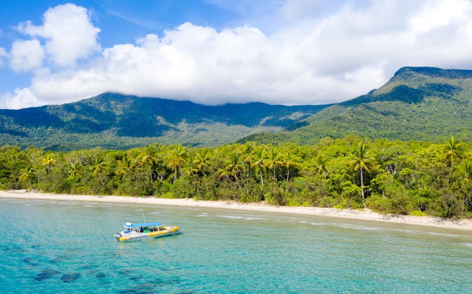 Boat near tropical shoreline with mountains, Great Barrier Reef Guided Snorkel & Eco Tour.