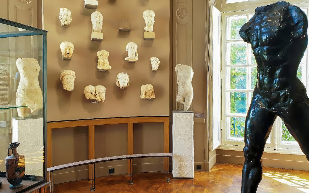 Rodin Museum gallery with sculptures and busts displayed on walls and pedestals.