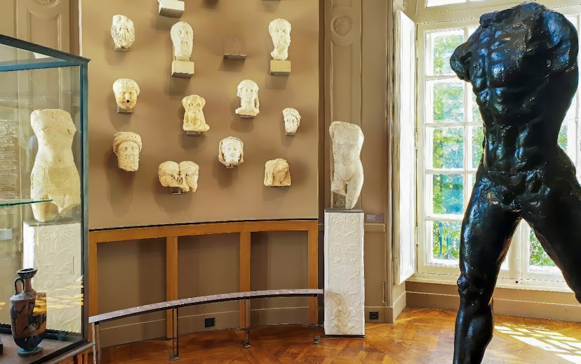 Rodin Museum gallery with sculptures and busts displayed on walls and pedestals.