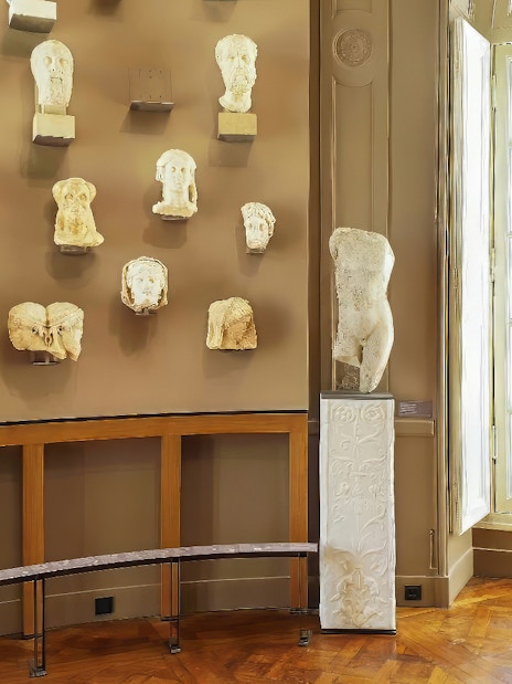 Rodin Museum gallery with sculptures and busts displayed on walls and pedestals.