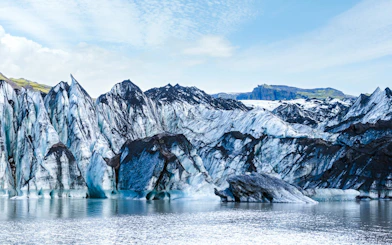 Solheimajokull glacier with icy peaks and surrounding water in Iceland.