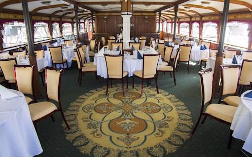 Elegant dining area on Budapest evening dinner cruise with set tables and ornate decor.