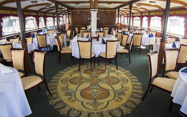 Elegant dining area on Budapest evening dinner cruise with set tables and ornate decor.