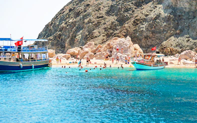 Boat trip to Suluada Island from Antalya with people swimming near rocky shore.