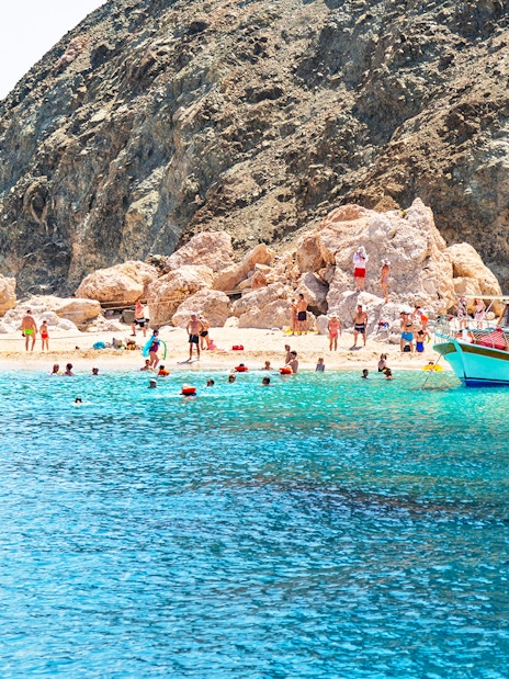 Boat trip to Suluada Island from Antalya with people swimming near rocky shore.