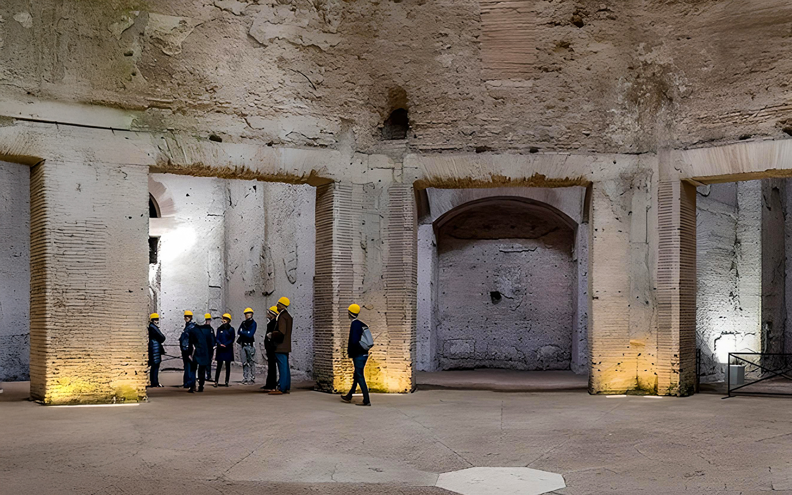 Visitors on a guided tour inside Domus Aurea, Rome, wearing helmets.